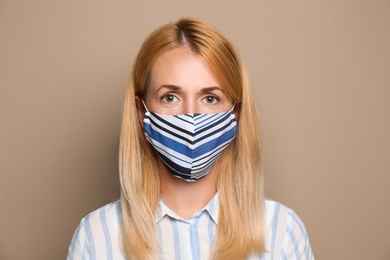 Woman wearing handmade cloth mask on beige background. Personal protective equipment during COVID-19 pandemic