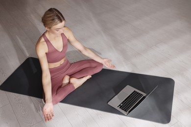 Beautiful woman watching online yoga class at home
