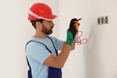 Professional electrician with tester checking voltage indoors