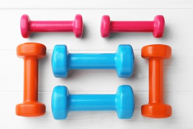 Different dumbbells on white wooden table, flat lay