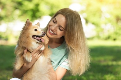 Photo of Young woman with her cute dog in park on sunny day