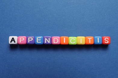 Word Appendicitis made of color cubes with letters on blue background, top view