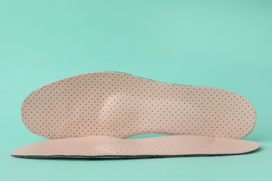 Beige comfortable orthopedic insoles on turquoise background
