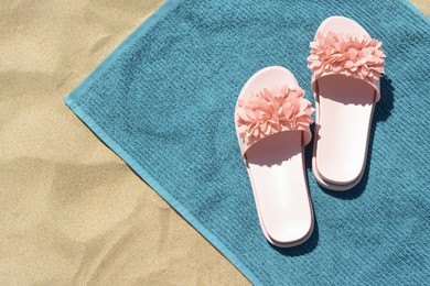 Photo of Towel and flip flops on sand, top view. Beach accessories