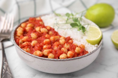 Photo of Delicious chickpea curry with rice in bowl on white marble table, closeup