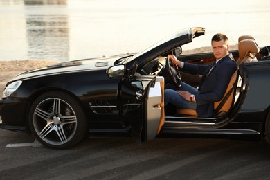 Young businessman in luxury convertible car outdoors