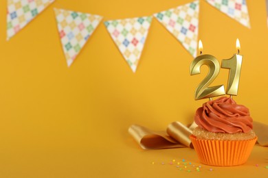 Coming of age party - 21th birthday. Delicious cupcake with number shaped candles on orange background, space for text