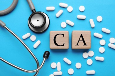 Photo of Stethoscope, pills and calcium symbol made of wooden cubes with letters on light blue background, flat lay
