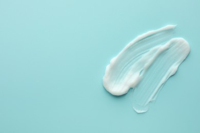 Samples of face cream on light blue background, top view. Space for text