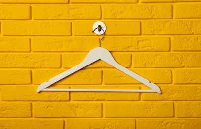 Empty clothes hanger on yellow brick wall