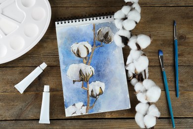 Painting of cotton flowers in sketchbook and art supplies on wooden table, flat lay