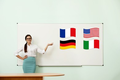Foreign languages teacher near whiteboard with different flags in modern classroom