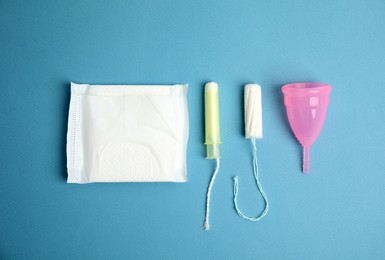 Tampon, pad and menstrual cup on blue background, flat lay