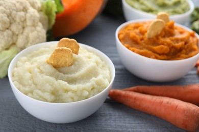 Bowls with different tasty puree and ingredients on light blue table, closeup