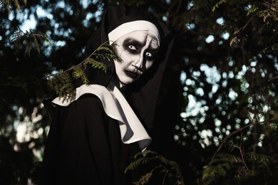 Portrait of scary devilish nun near tree outdoors. Halloween party look