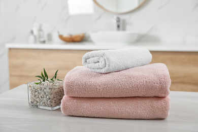 Fresh towels and salt on white table in bathroom