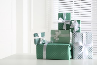 Heap of wrapped gift boxes on white table, space for text. Happy holiday