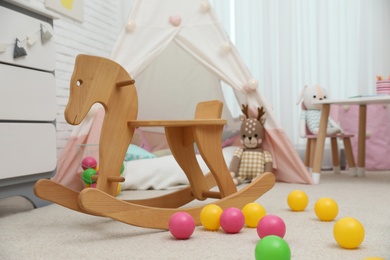 Photo of Wooden rocking horse and toy balls in playroom. Interior design