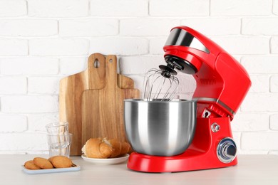 Photo of Modern red stand mixer, croissant and cookies on white wooden table