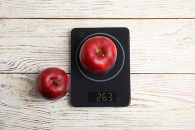 Ripe red apples and electronic scales on white wooden table, flat lay