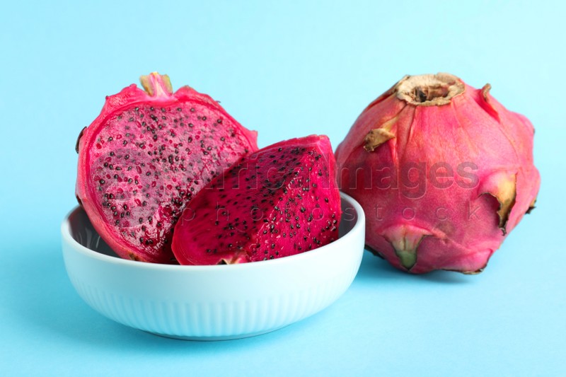 Delicious cut and whole red pitahaya fruits on light blue background