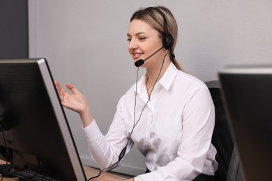 Young call center operator with headset working in modern office