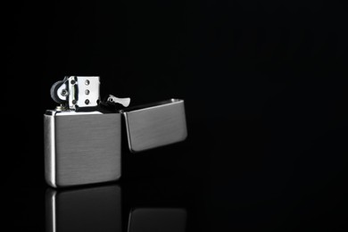 Photo of Gray metallic cigarette lighter on black background, space for text