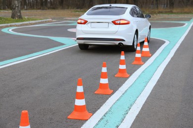 Modern car on driving school test track with traffic cones