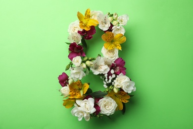 Number 8 made of beautiful flowers on green background, flat lay. International Women's day