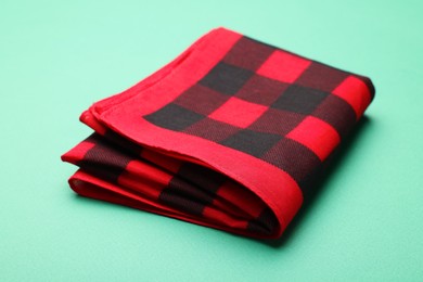 Folded red checkered bandana on turquoise background