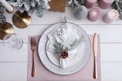 Photo of Festive place setting with beautiful dishware, cutlery and cone for Christmas dinner on white wooden table, flat lay
