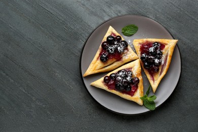 Photo of Fresh tasty puff pastry with sugar powder, jam, sweet berries and mint on grey table, top view. Space for text