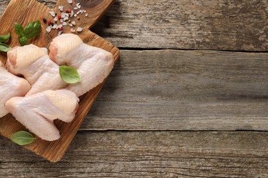 Raw chicken wings with basil and spices on wooden table, top view. Space for text