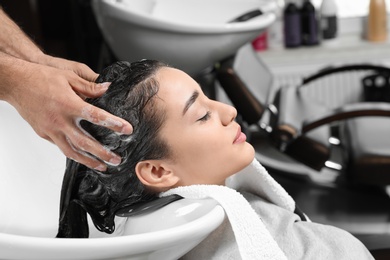 Photo of Stylist washing client's hair at sink in beauty salon