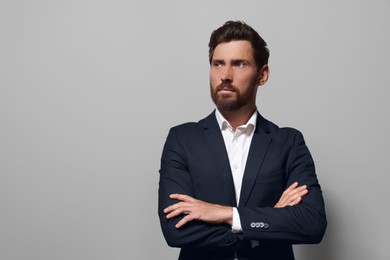 Portrait of handsome bearded man in suit looking away on light grey background. Space for text