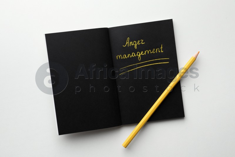 Photo of Black sketchbook with words Anger Management and pencil on white background, top view