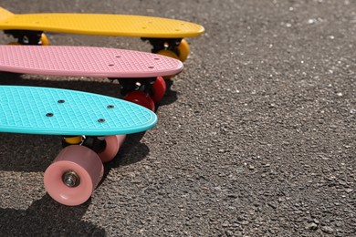 Different modern colorful skateboards on asphalt road  outdoors, closeup. Space for text