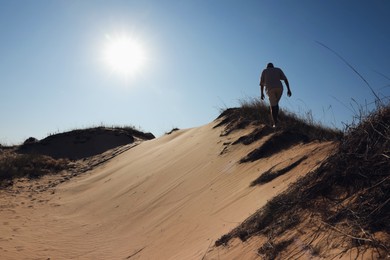 Man walking through desert on sunny day, back view