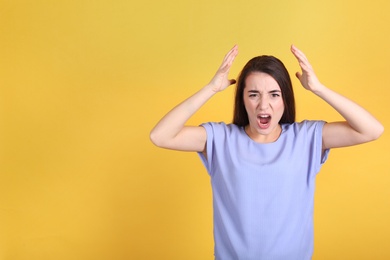 Portrait of stressed young woman on yellow background. Space for text