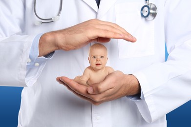 Surrogacy concept. Doctor holding cute little baby on blue background, closeup