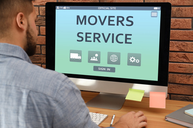 Young man using computer to order movers service in office, closeup