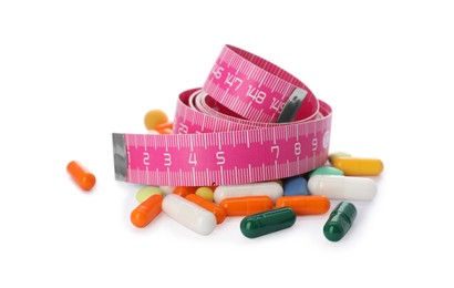 Weight loss pills and measuring tape on white background