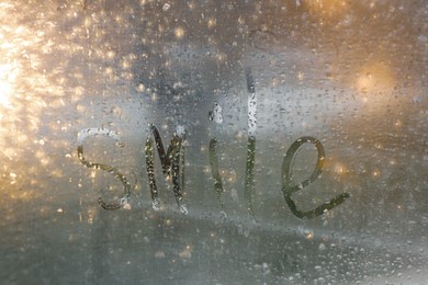 Word Smile written on foggy window. Rainy weather