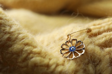 Evil eye safety pin on knitted clothing, closeup