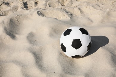 Soccer ball on sand, space for text. Football equipment