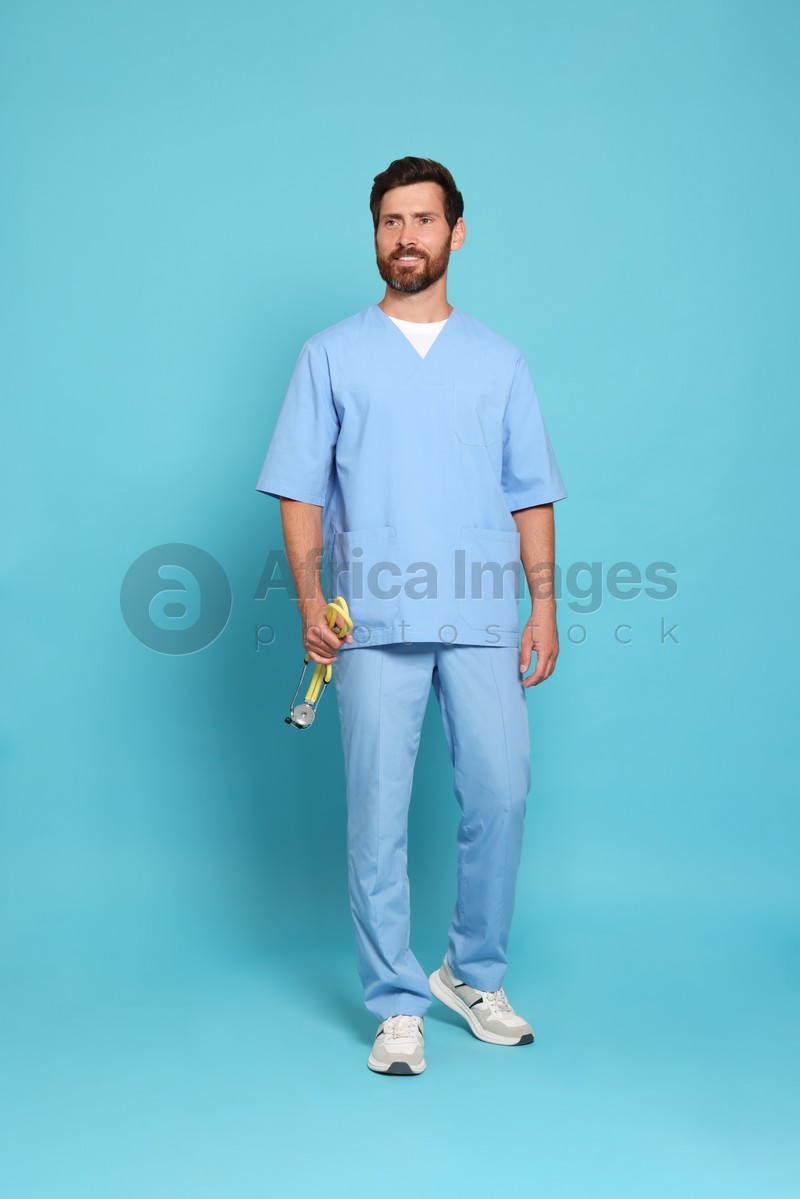 Photo of Full length portrait of doctor with stethoscope on light blue background