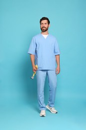 Full length portrait of doctor with stethoscope on light blue background