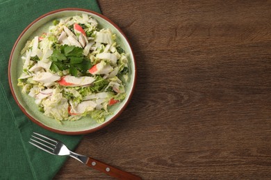 Photo of Delicious salad with Chinese cabbage, crab sticks and parsley on wooden table, top view. Space for text