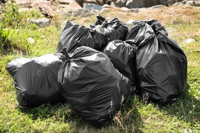 Many trash bags full of garbage on green grass outdoors. Environmental Pollution concept
