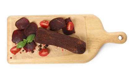 Delicious dry-cured beef basturma with basil, peppercorns and tomatoes on white background, top view